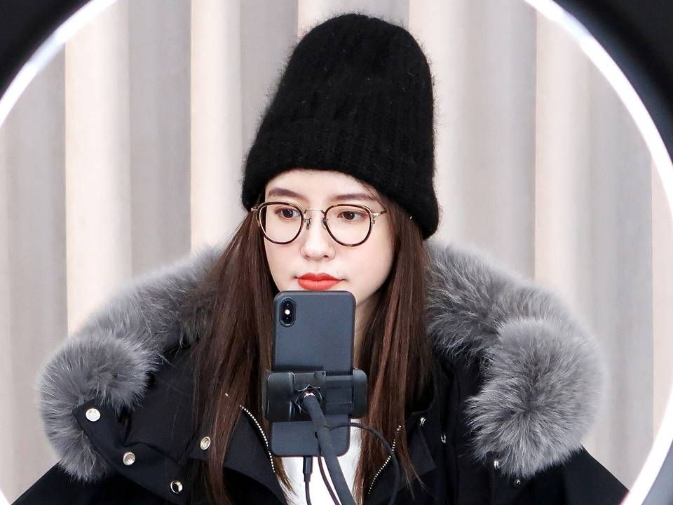 Den kinesiske online celebrity Zhang Dayi checker kommentarerne på sin telefon under en live-streaming. | Foto: Brenda Goh/Reuters/Ritzau Scanpix